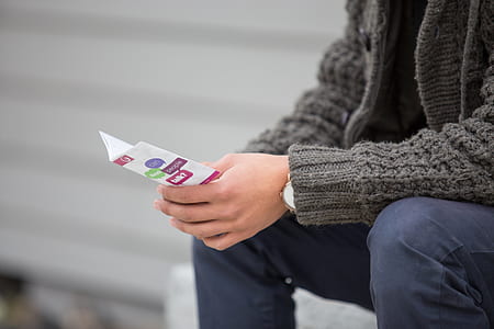 person wearing black sweater holding printer paper while sitting thumbnail
