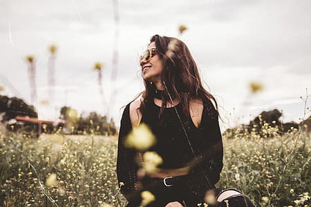 side view of woman sitting on green grass field laughing thumbnail