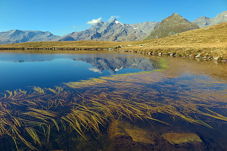 body of water near mountain during daytime thumbnail