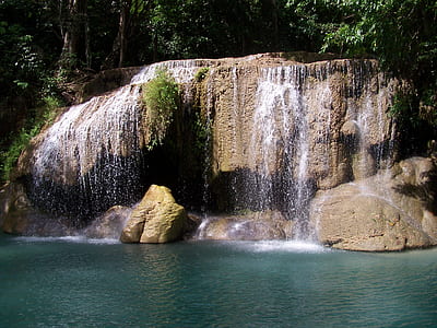 brown waterfalls surrounded by trees during daytime thumbnail