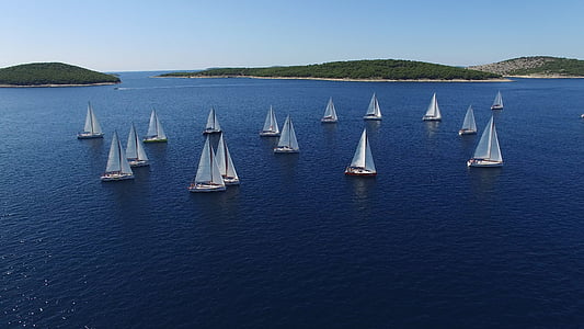 aerial view photography of white sailboats at sea surrounded by islands under clear sky during daytime thumbnail
