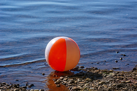 white and orange plastic ball on seashore thumbnail