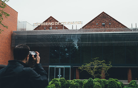 man taking photo of brown and black building thumbnail