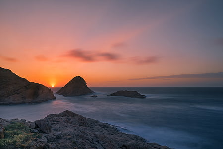 rock formation near body of water with sunset background thumbnail