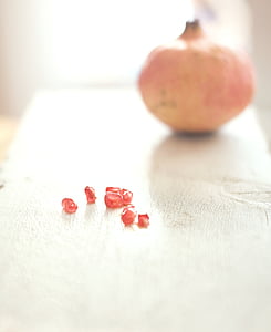 red kernels near round pink fruit above white surface thumbnail