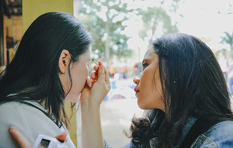 Woman Taking Makeup on Woman Near Window thumbnail