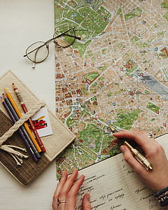 person holding brown click pen pointing map beside black framed eyeglases thumbnail