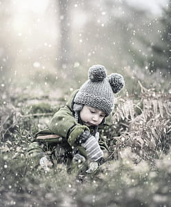 toddler sitting on grass under snow thumbnail