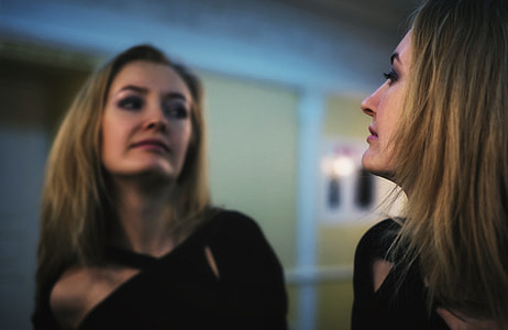 selective focus photography of woman in black top looking on mirror thumbnail