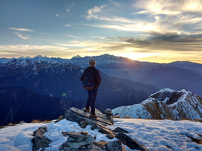 person standing on gray hill near mountain under blue sky thumbnail