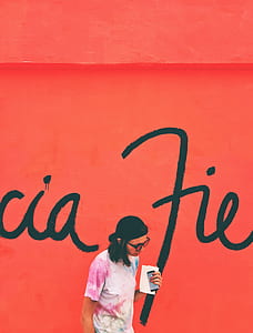 woman holding iPhone standing in front of wall thumbnail