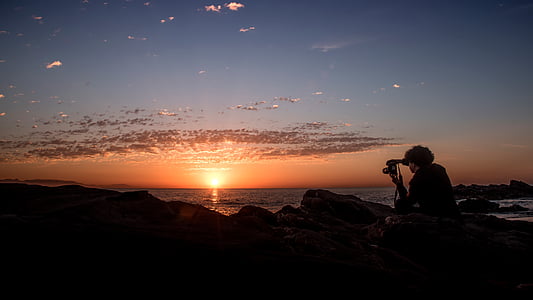 silhouette of person holding camera during golden hour thumbnail