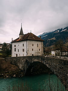 bridge to white concrete house near mountain thumbnail
