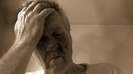 man in crew-neck shirt holding head in sepia tone photography thumbnail