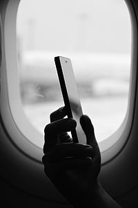 person sitting near airliner window while holding smartphone thumbnail