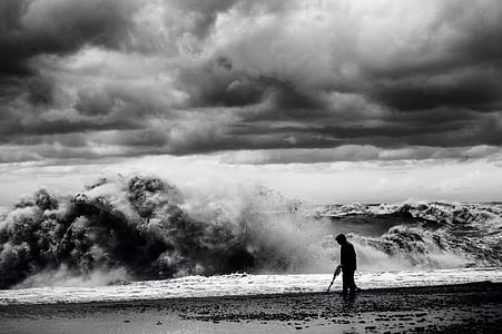 silhouette of man on shore with huge waves and cloudy sky thumbnail