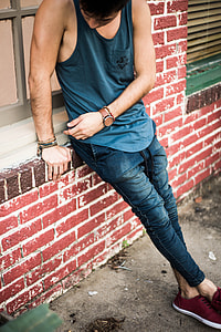 man in blue tank top and blue jeans sitting on windowsill thumbnail