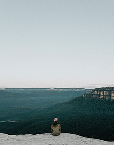 person sitting on mountain tip during daytime thumbnail