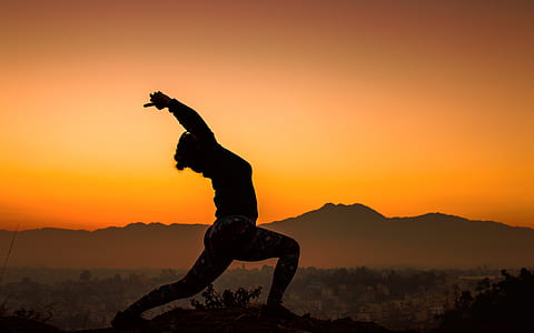 silhouette of person doing yoga with mountains at distance thumbnail
