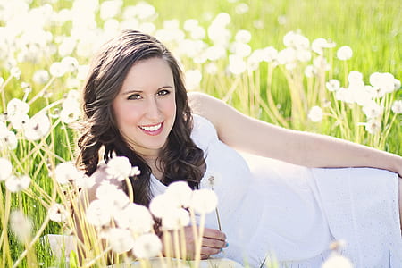 woman wearing white dress lying on flower fields thumbnail