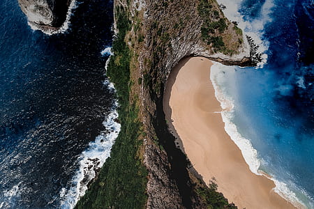 brown and green mountain in between body of water thumbnail