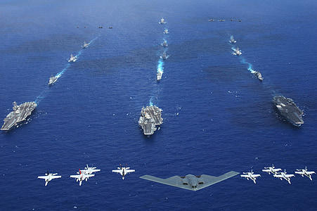 stealth fighter and jet plane over aircraft carrier on large blue body of water at daytime thumbnail