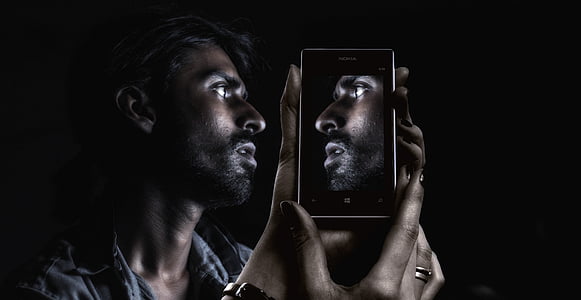 man in blue shirt holding Android smartphone thumbnail