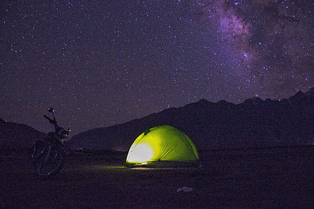 green tent beside motorcycle during nighttime thumbnail