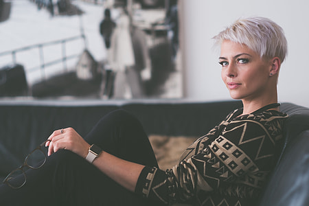 woman in black and white tribal print sweater sitting on black couch in tilt shift photography thumbnail