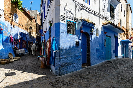 person walking between blue buildings thumbnail