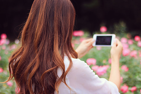 woman in white long sleeved shirt holding a smartphone thumbnail