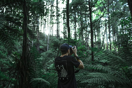 man holding camera standing on forest during daytime thumbnail