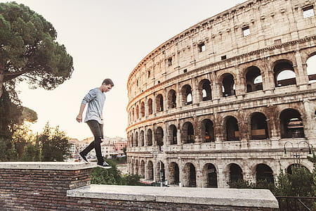 man walking above wall beside colosseum at daytime thumbnail