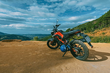 Photography of Orange and Black Sports Motorcycle Near a Cliff thumbnail