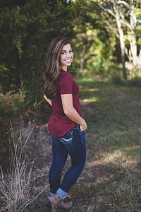 woman in maroon shirt and blue jeans standing outdoor thumbnail