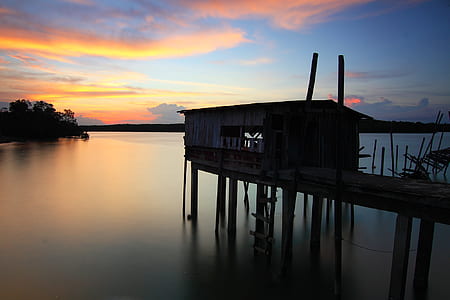 Silhouette of House on Top of Ocean Water during Sunset thumbnail