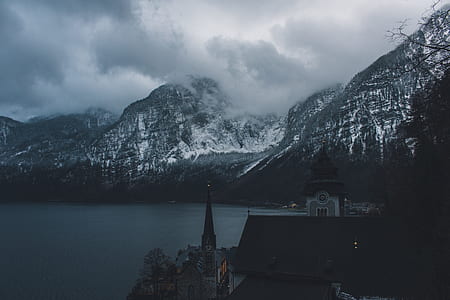 snow-covered mountain near body of water during cloudy day thumbnail