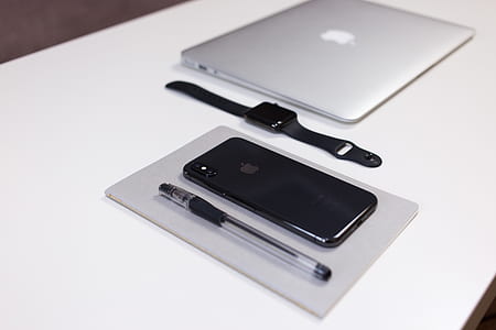 space gray iPhone X beside black pen, space gray aluminum case, Apple Watch with black Sport band, and MacBook Air thumbnail