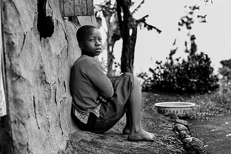 Greyscale Photography of Boy Sitting Behind Wall thumbnail
