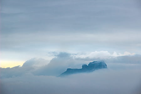 black rocky mountain surrounded with white clouds thumbnail