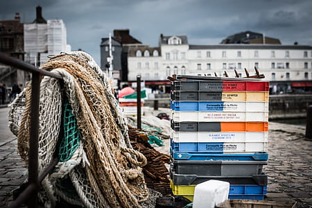 selective focus photography of pile crates near brown fish net hanged on black metal bar thumbnail