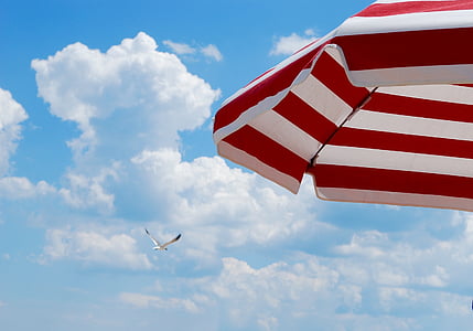 red and white striped parasol under cloudy sky thumbnail