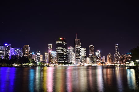 photo of city skyline reflecting on calm body of water at nighttime thumbnail