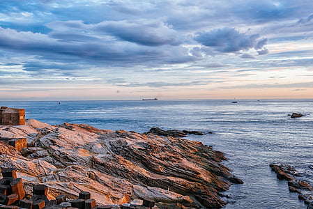 rock formation near body of water under cloudy sky at daytime thumbnail