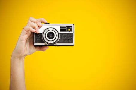 person holding black and gray camera with yellow background thumbnail
