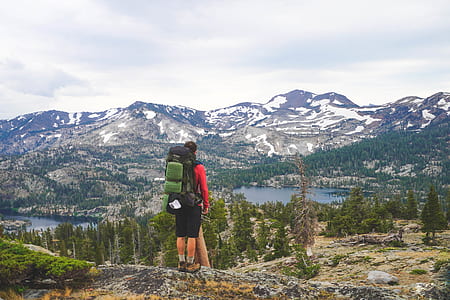 person wearing backpack standing on hill during daytime thumbnail