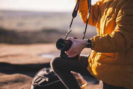 shallow focus photography of man holding black camera thumbnail