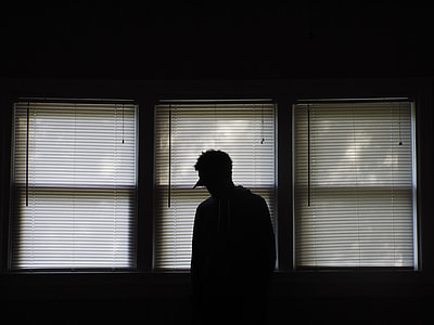 silhouette of person standing beside white window blinds inside room thumbnail