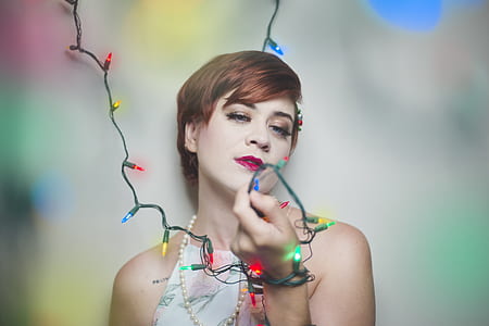 woman lean back on the wall holding string lights thumbnail