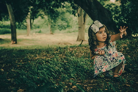 girl sitting on green grass during daytime thumbnail